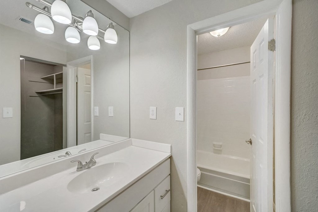 a bathroom with a mirror, vanity, and tub and shower at Hills at Hoover 35216