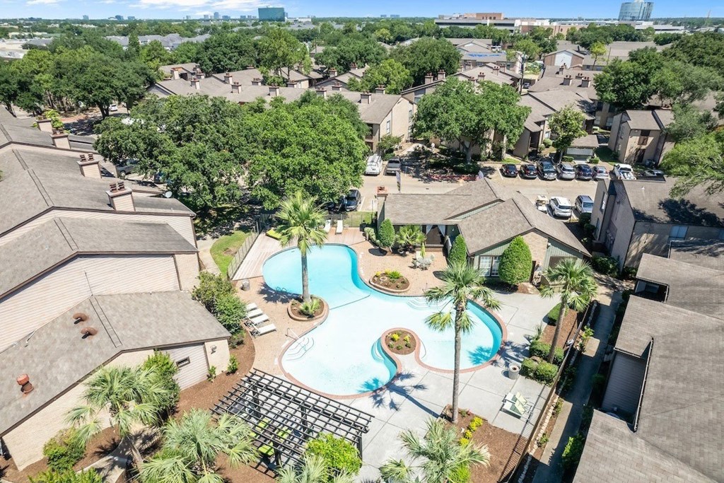 A bird's eye view of a residential area with a swimming pool and palm trees.