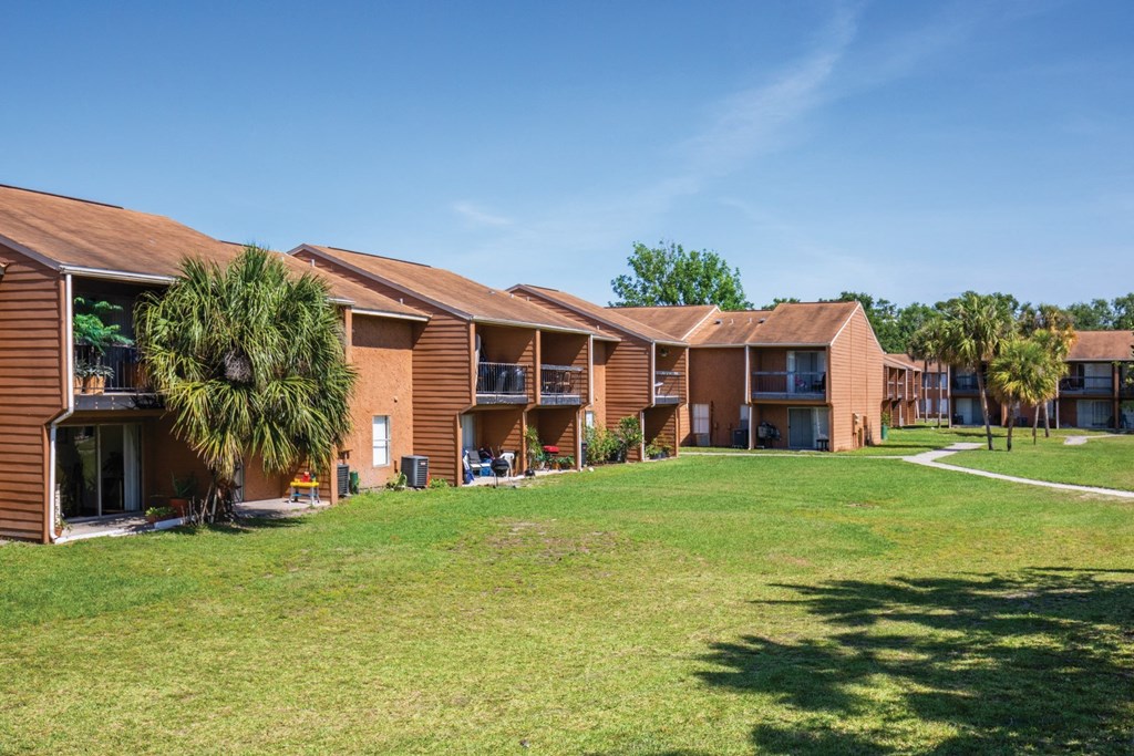 a row of apartments with a green lawn and palm trees