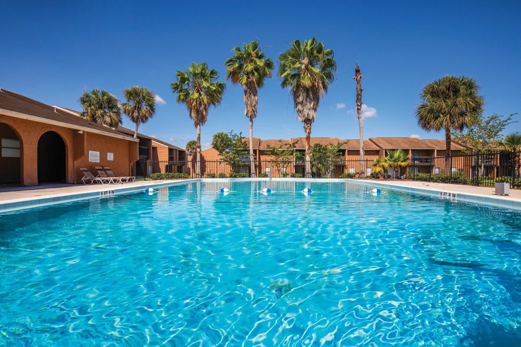 a large swimming pool with palm trees in front of a building