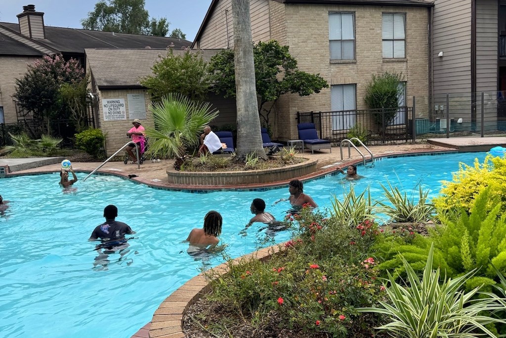 People are swimming in a pool surrounded by plants.
