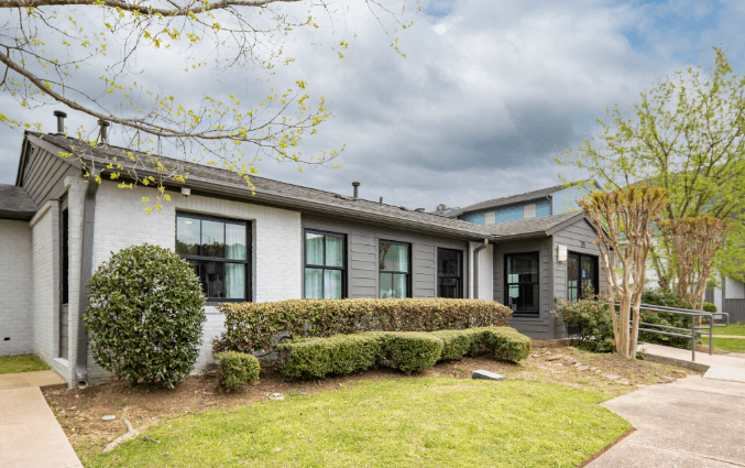 a gray and white building with a green lawn and bushes in front of it at Crestwood Green, LLC, Birmingham, AL