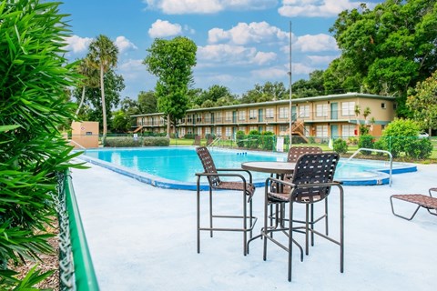 A poolside table with chairs is set up by a swimming pool.
