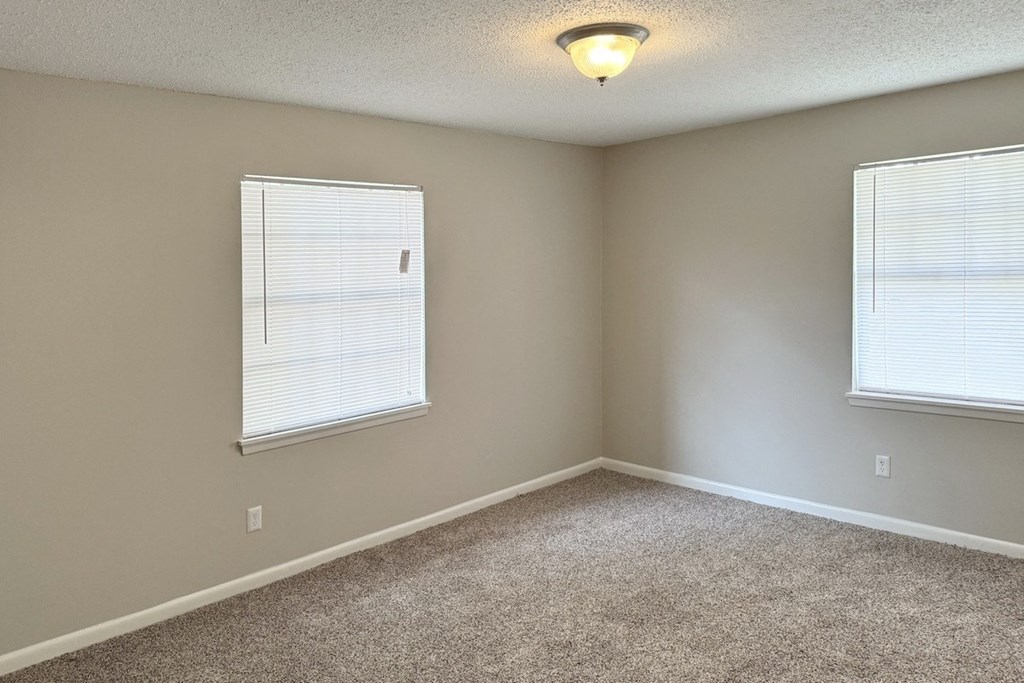 an empty bedroom with two windows and a carpeted floor an empty bedroom with two windows and a carpeted floor at Spring Lake Cove Apartments, Birmingham, AL 35215