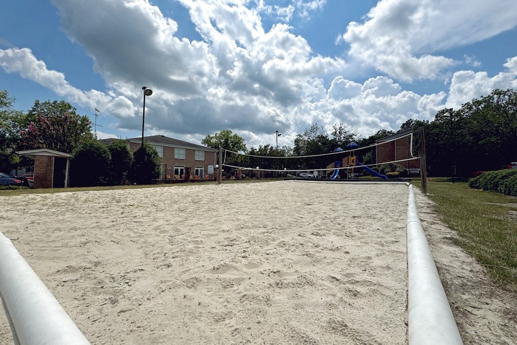 a sand volleyball court with a building in the background a sand volleyball court with a building in the background at Ascot Place Apartments, Alabama