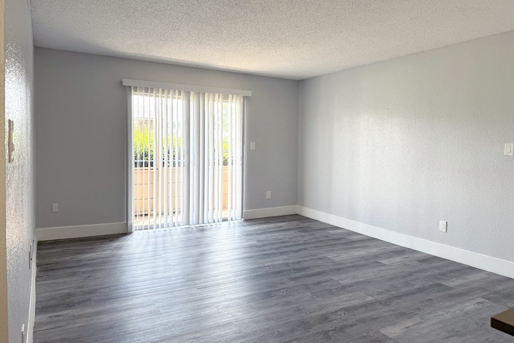an empty living room with wood floors and a sliding glass door an empty living room with wood floors and a sliding glass door at Ascot Place Apartments, Birmingham, AL