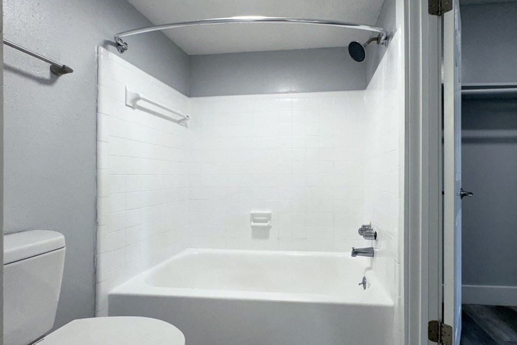 a white bathroom with a tub and a toilet a white bathroom with a tub and a toilet at Ascot Place Apartments, Alabama
