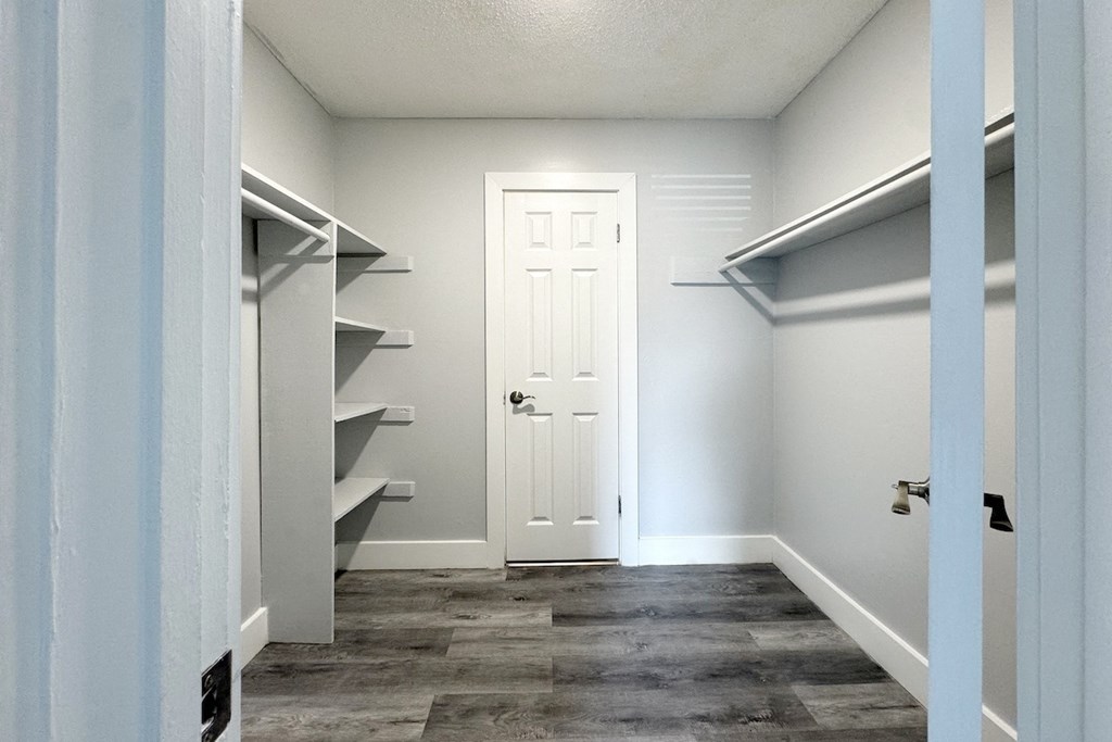 a walk in closet with a white door and a hallway with shelves and a door a walk in closet with a white door and a hallway with shelves and a door at Ascot Place Apartments, Birmingham Alabama