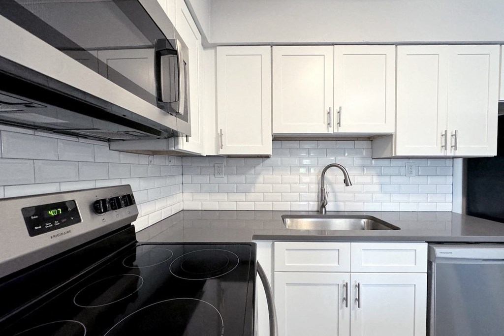 a white kitchen with black appliances and white cabinets a white kitchen with black appliances and white cabinets at Ascot Place Apartments, Birmingham, AL 35235