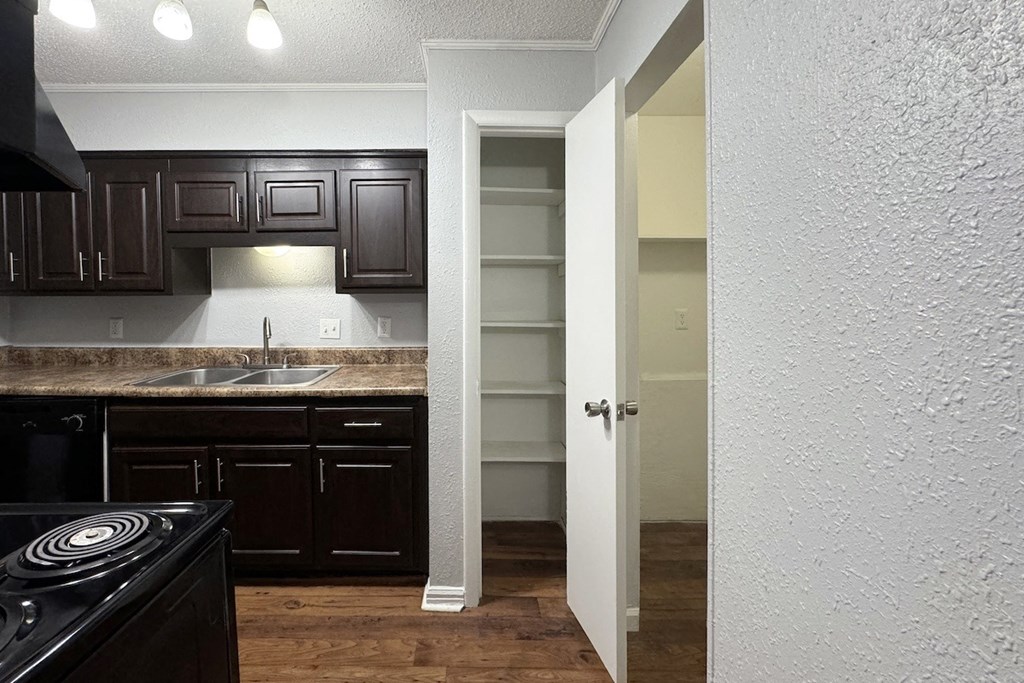 a kitchen with dark cabinets and a sink and an open doorway a kitchen with dark cabinets and a sink and an open doorway at Ascot Place Apartments, Birmingham