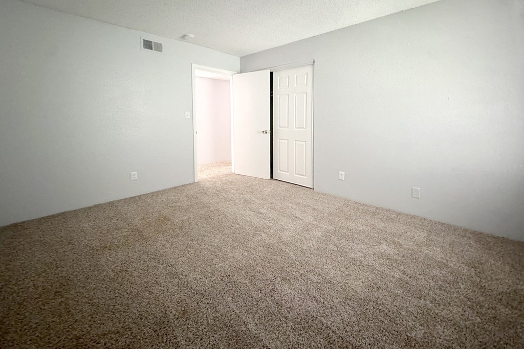 an empty room with a carpeted floor and a white door an empty room with a carpeted floor and a white door at Ascot Place Apartments, Alabama