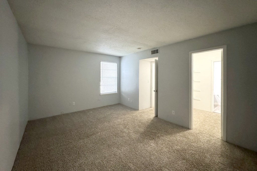 an empty living room with carpet and a door to a bedroom an empty living room with carpet and a door to a bedroom at Ascot Place Apartments, Birmingham, AL