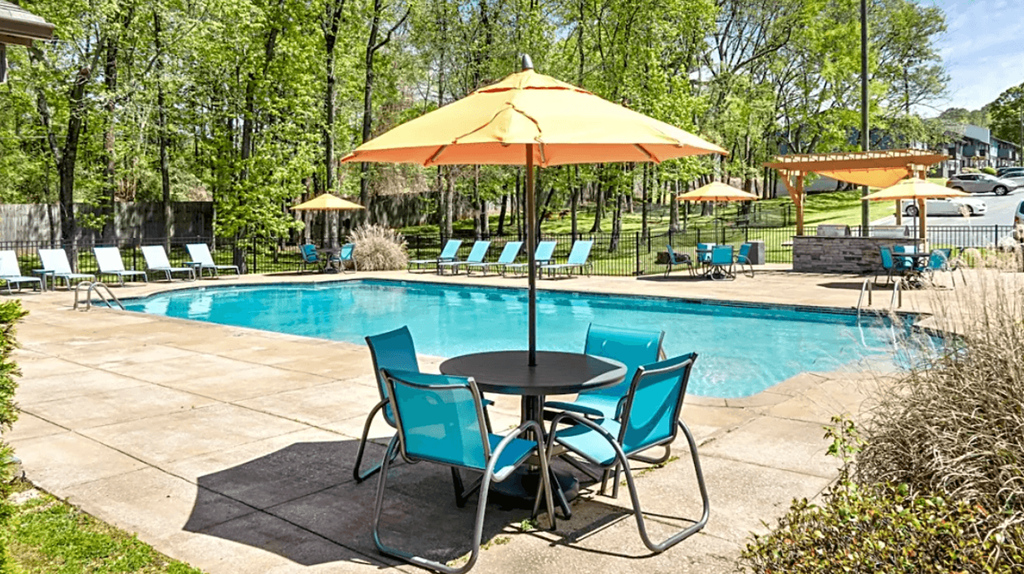 a swimming pool with a table and chairs and an umbrella at Crestwood Green, LLC, Birmingham