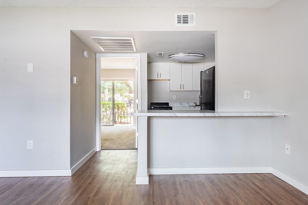 a kitchen and living room in an apartment with hardwood floors and white walls