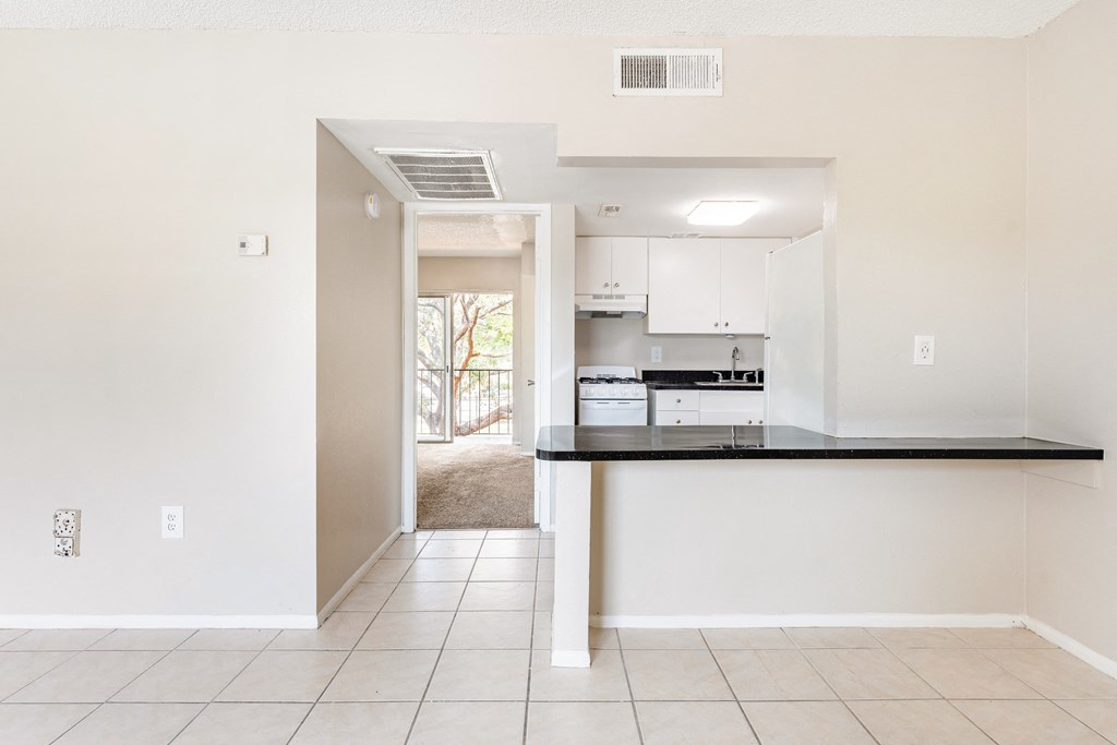 a kitchen with white cabinets and a black counter top