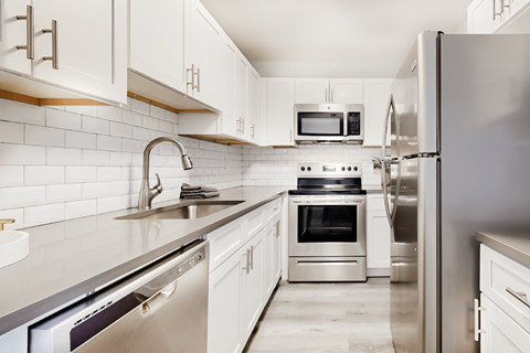 a modern kitchen with stainless steel appliances and white cabinets