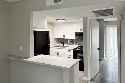 A kitchen with a black refrigerator and white cabinets.