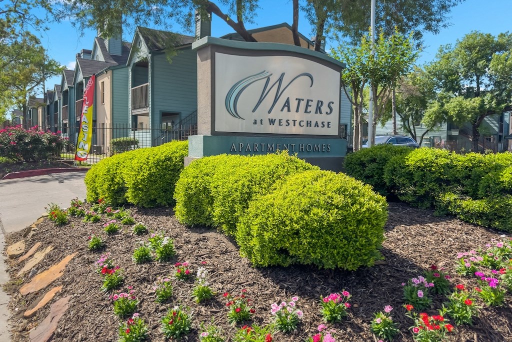 The Waters at Westchase Monument sign surrounded by flowers and lush bushes