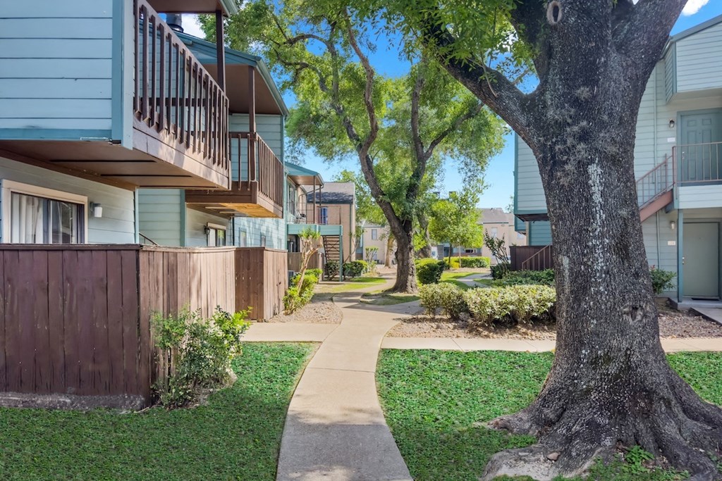 a lush courtyard with neat sidewalks between residential buildings at Waters at Westchase Apartments
