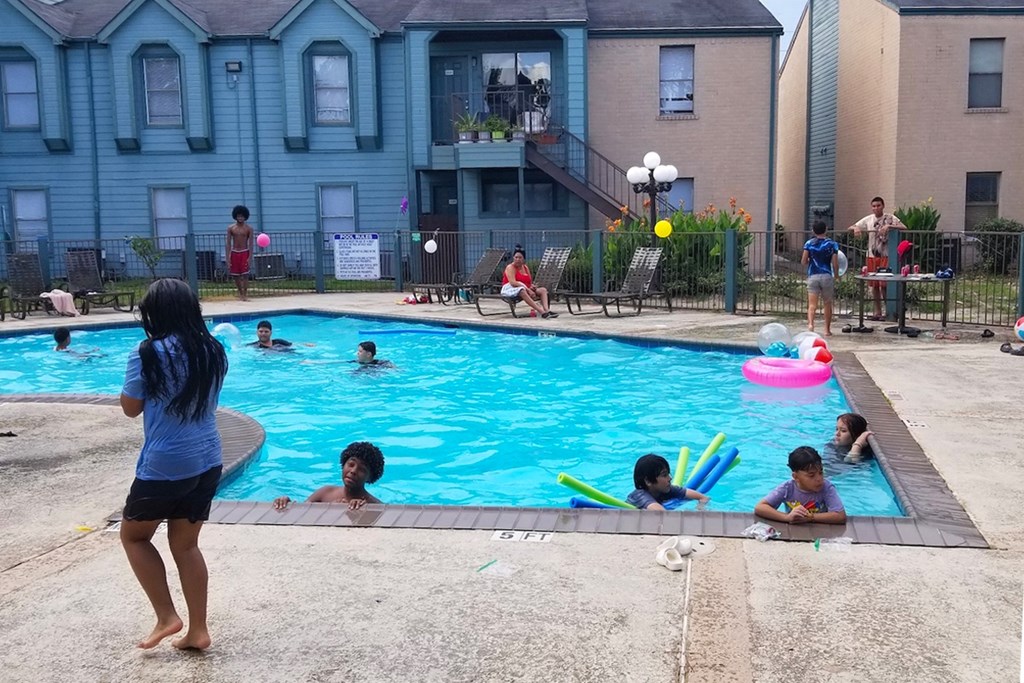 A girl standing by the pool full of people at Waters at Westchase