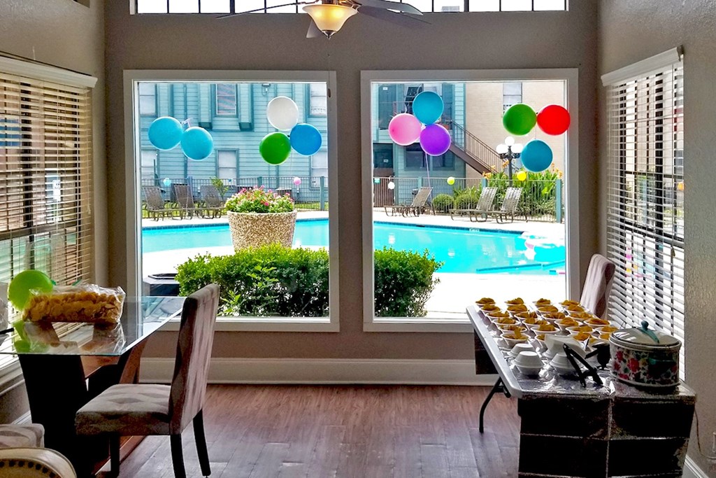 A table with food on it is in front of a window with a view of a pool.