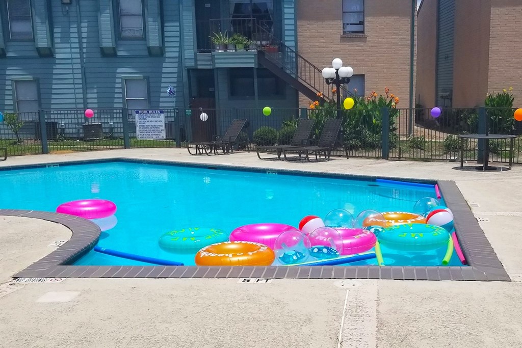 A pool with a floats and noodles and beach balls