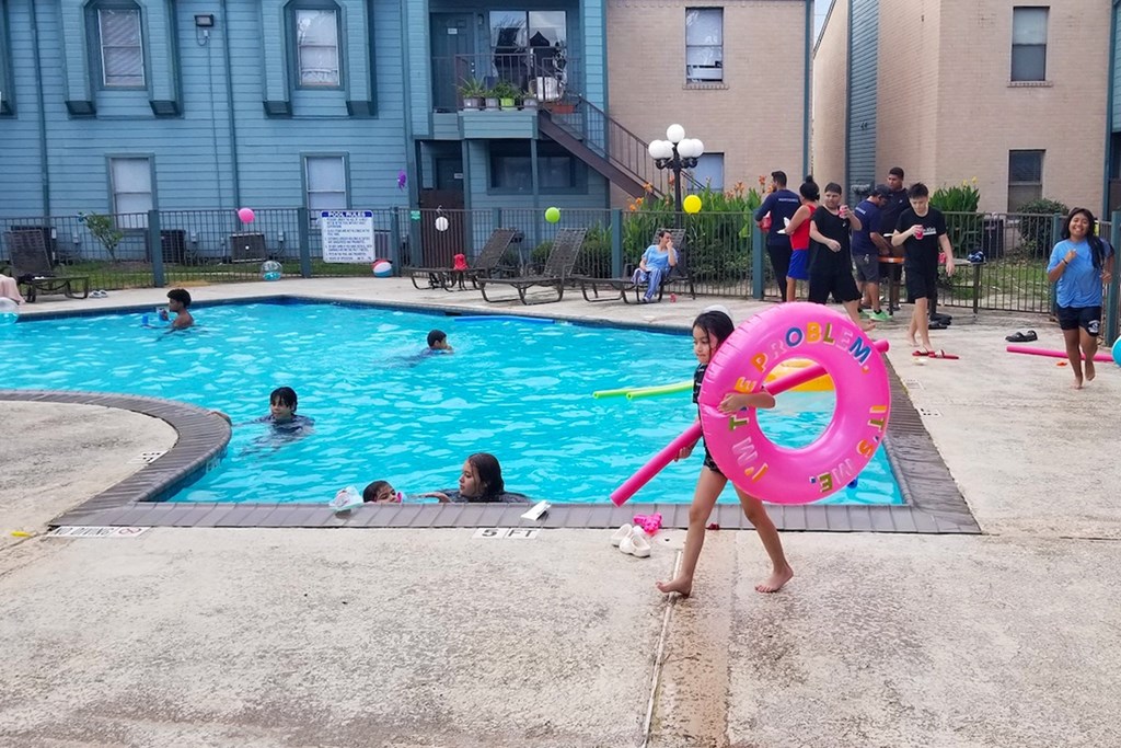 A person is holding a pink inflatable ring at a pool party