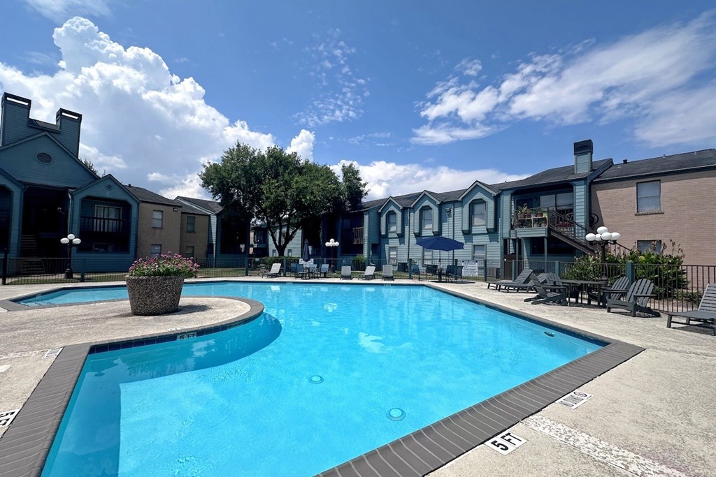 A large swimming pool surrounded by lounge chairs and umbrellas.