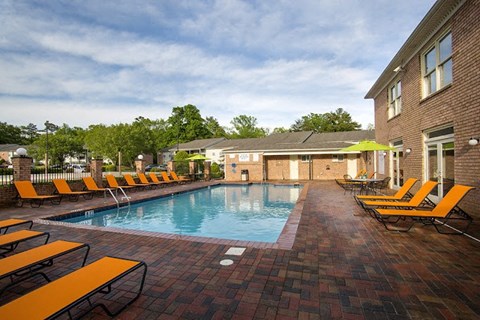 a swimming pool with yellow chairs next to a brick building