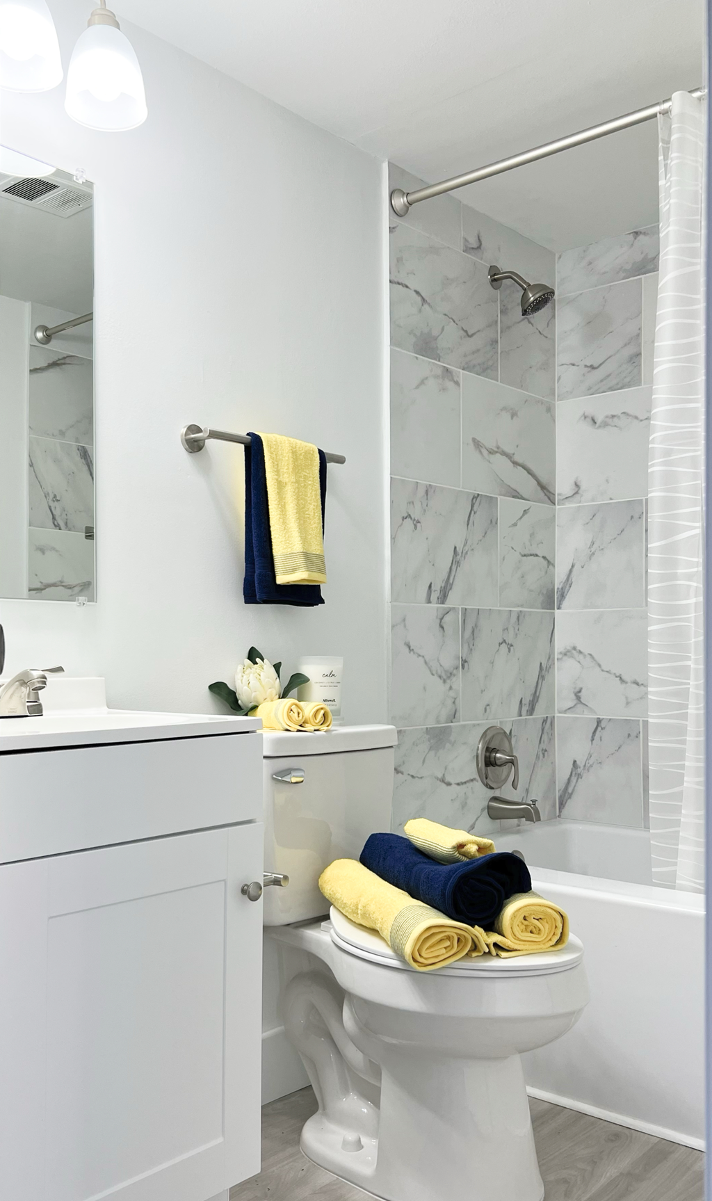 a small bathroom with a white vanity and toilet and a shower with a glass door