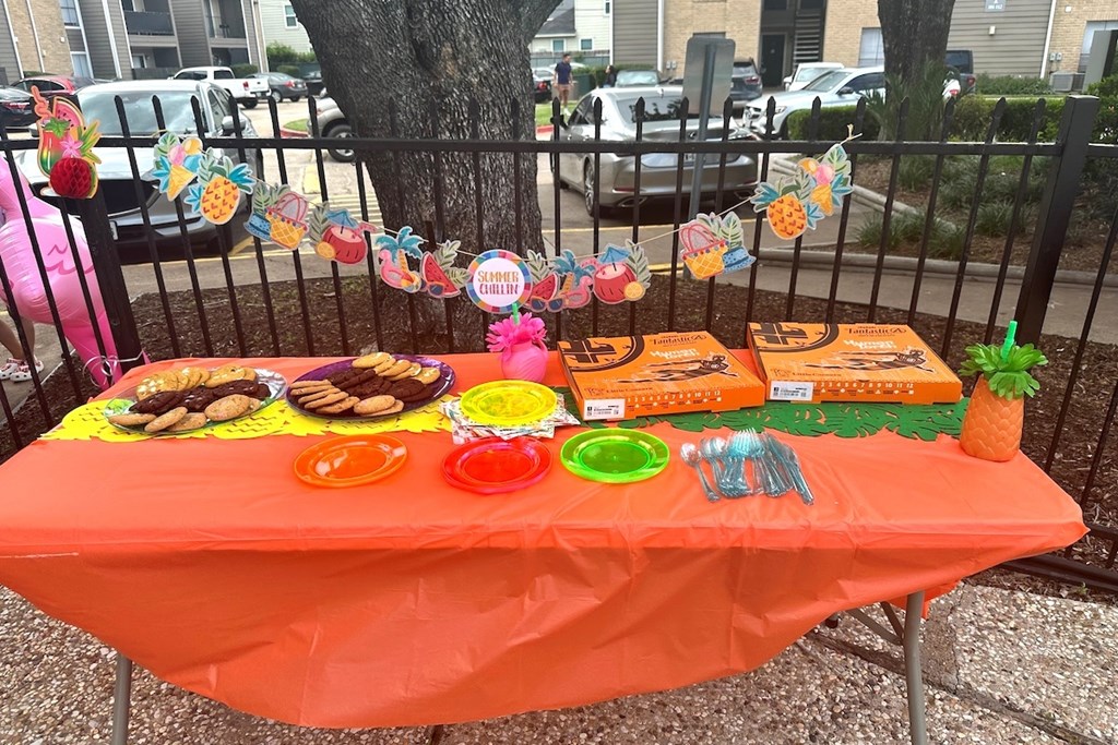 A table with an orange tablecloth is set up for an event.