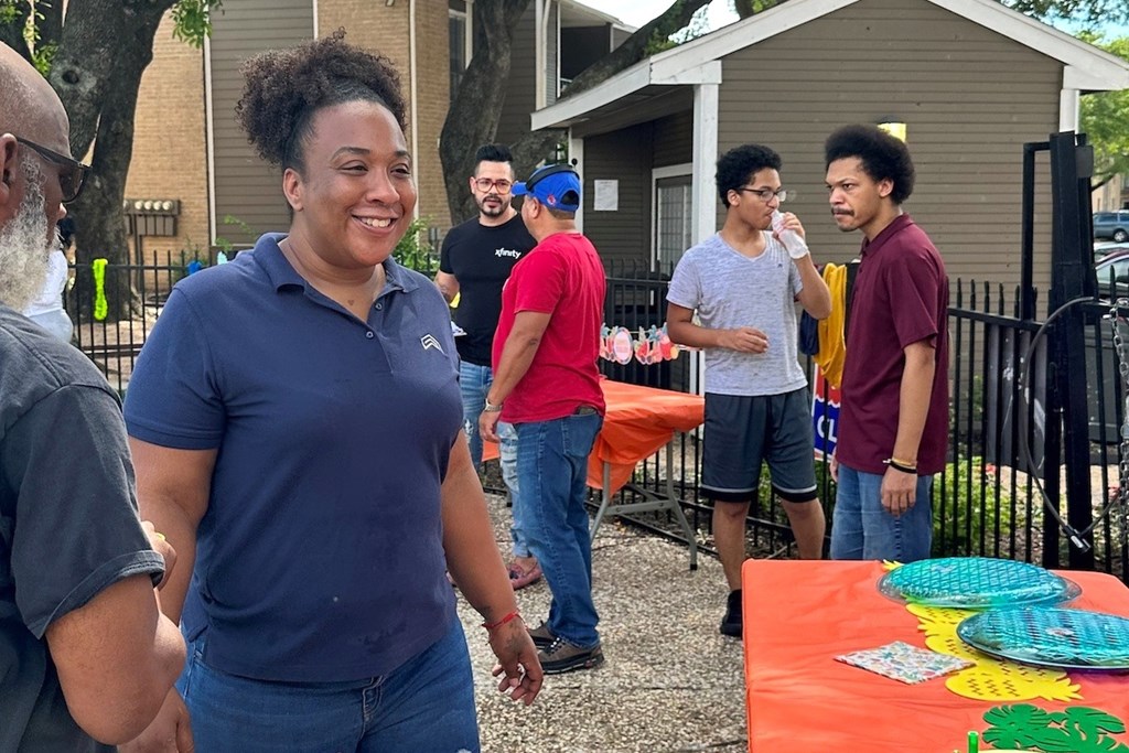 A group of people are gathered around a table with a colorful tablecloth.