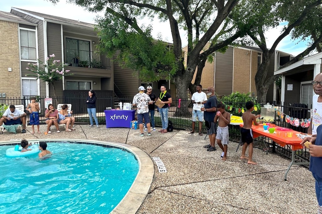 A group of people are gathered around a pool in a backyard.