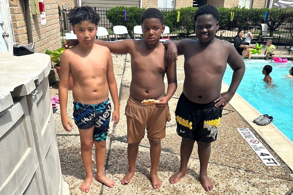 Three boys standing by a pool.