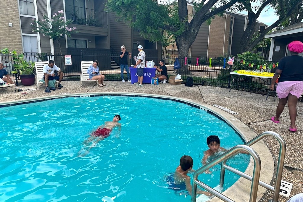 People are swimming in a pool with a blue tarp in the background.