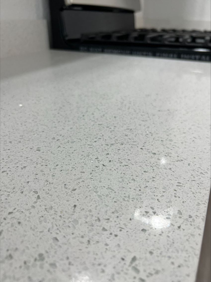 a close up of a white counter top with a stove in the background - Photo Gallery