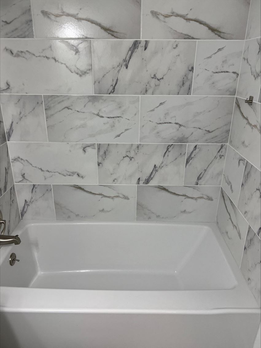 a bathtub in a bathroom with a tiled wall and floor - Photo Gallery