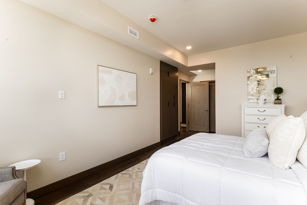A bedroom with a white bed and a painting on the wall.