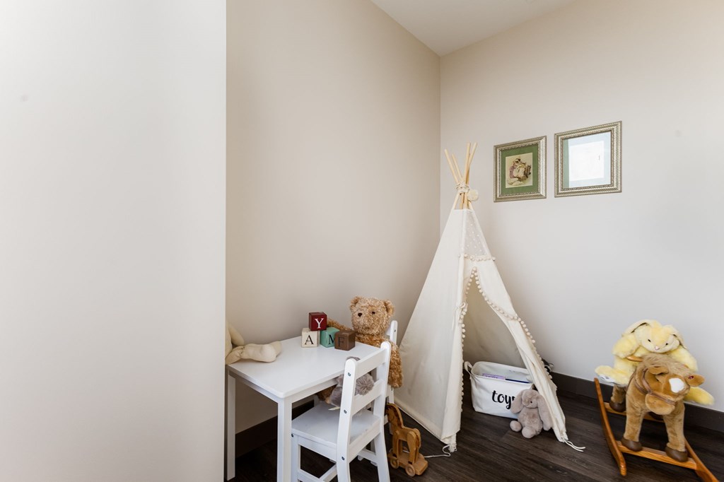 A child's room with a teepee, rocking horse, and teddy bears.