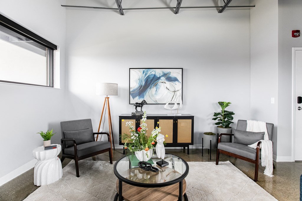 a living room with a table and chairs and a painting on the wall