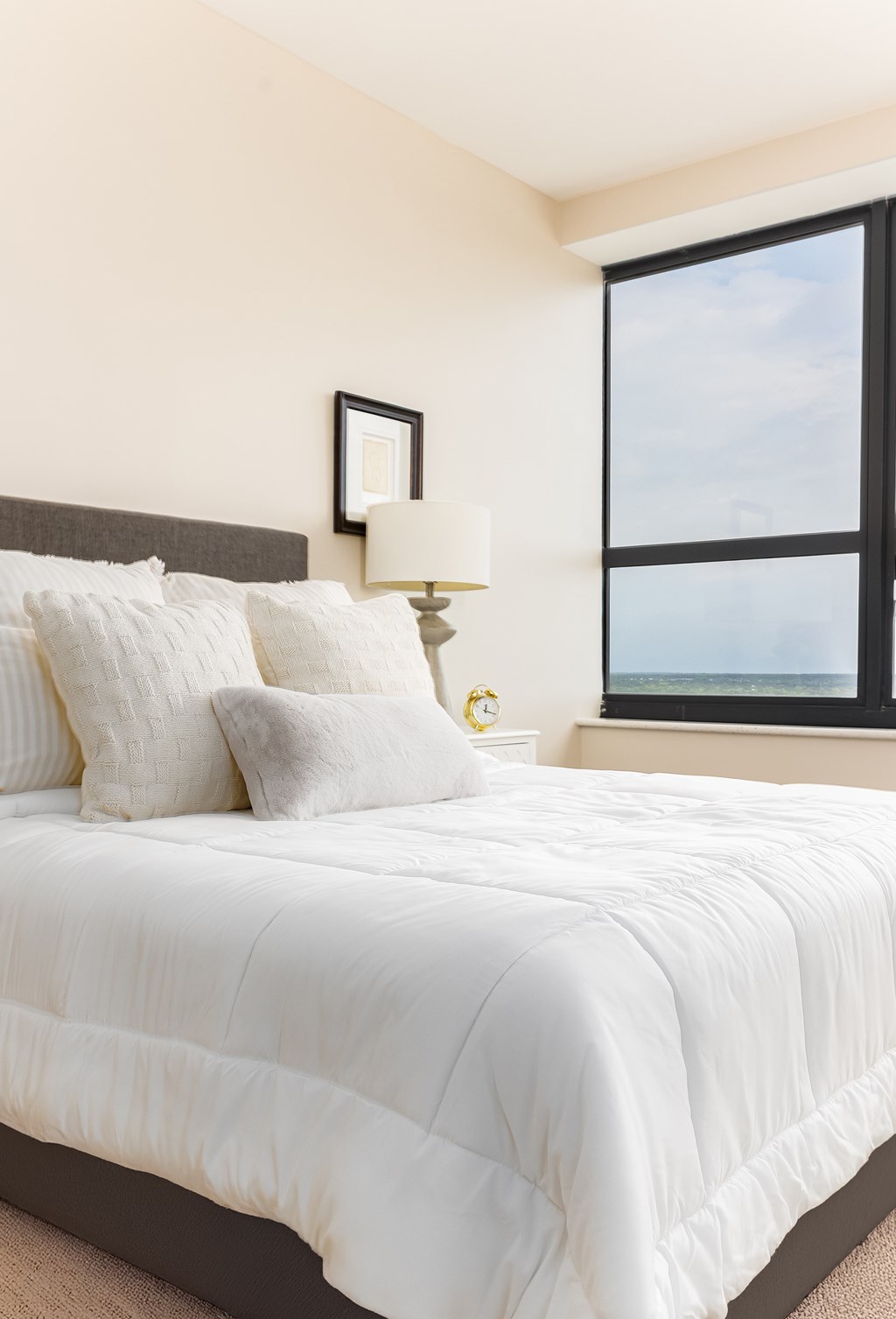 A bed with white bedding and a white pillow is in front of a window.