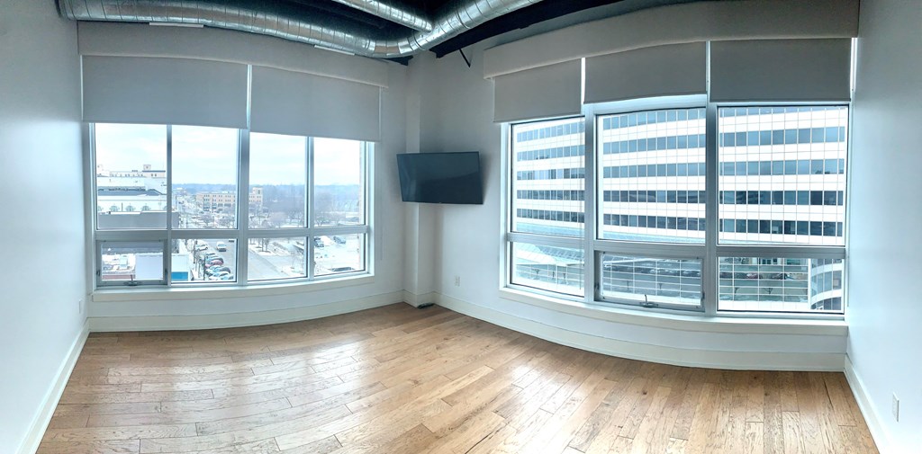 an empty room with large windows and a wood floor