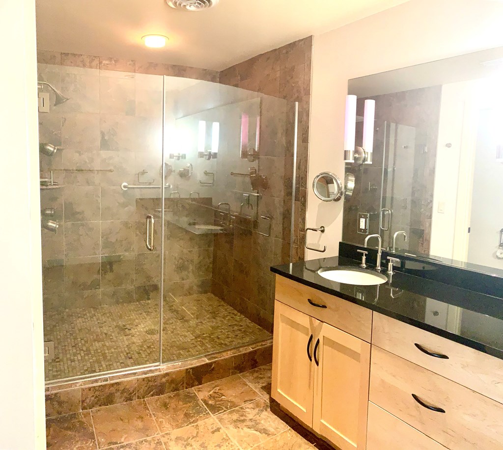a bathroom with a shower and a sink and a mirror