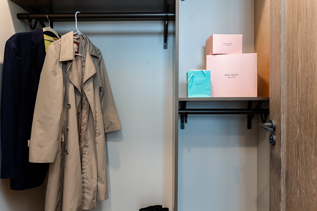 A beige trench coat is hanging on a hook.