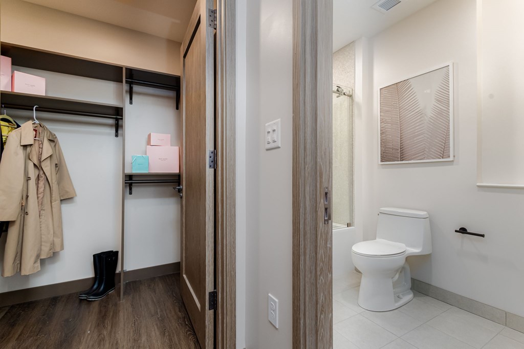 A bathroom with a toilet and a coat hanging up.