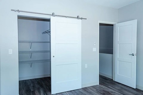 A white closet with a sliding door and a white door.