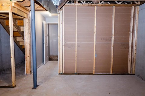 A room under construction with wooden framing and a staircase on the left.