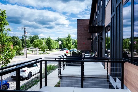 A balcony with a railing overlooks a parking lot and trees.