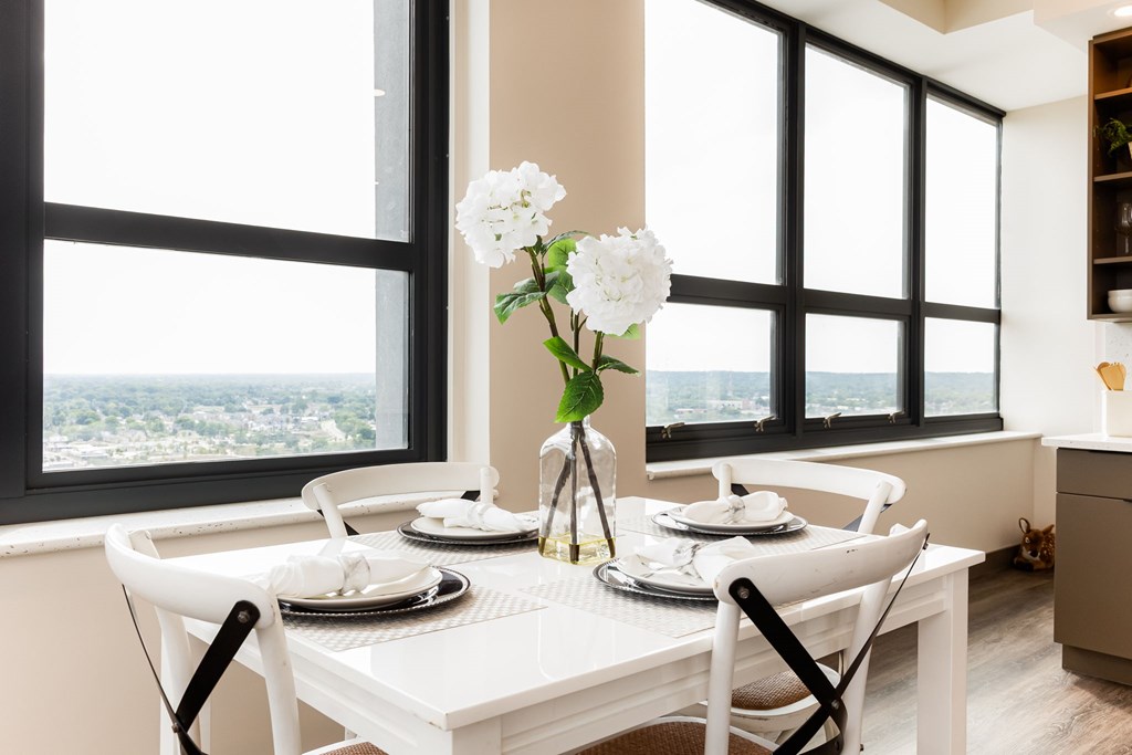 A dining table set with plates and a vase of flowers in front of a window.