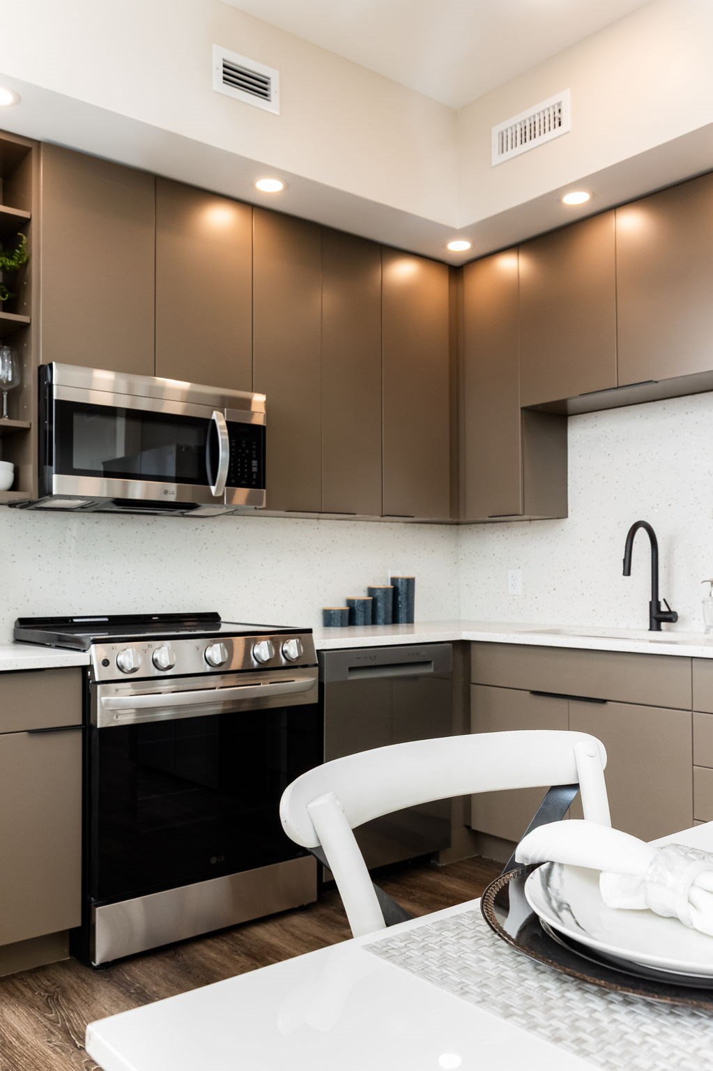 A modern kitchen with a white chair and stainless steel appliances.